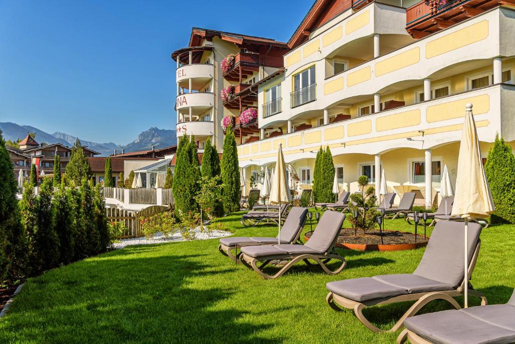 hotel z leżakami i parasolami na dziedzińcu w obiekcie Hotel Alpina Wellness & Spa Resort w mieście Kössen