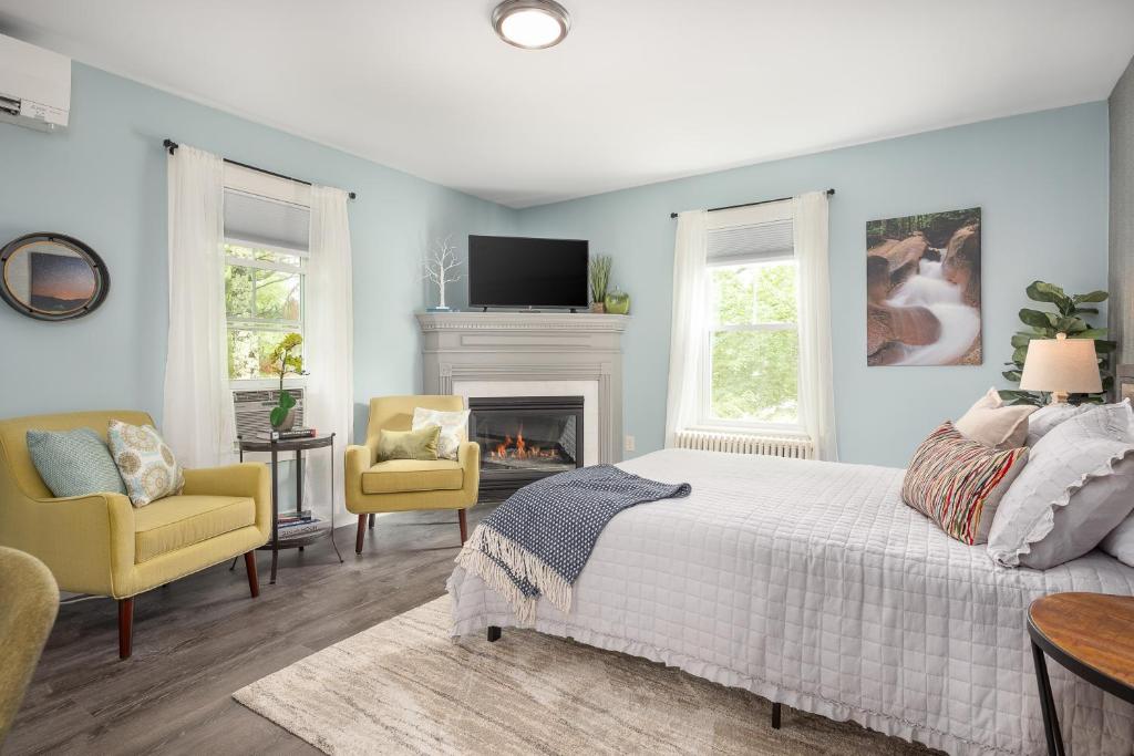 a bedroom with a bed and two chairs and a fireplace at TuckAway Suites at East Branch in Intervale