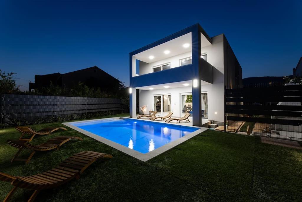 a house with a swimming pool in the backyard at Vila MaMe apartman s privatnim bazenom, besplatnim parkingom i wi - fi in Kaštela