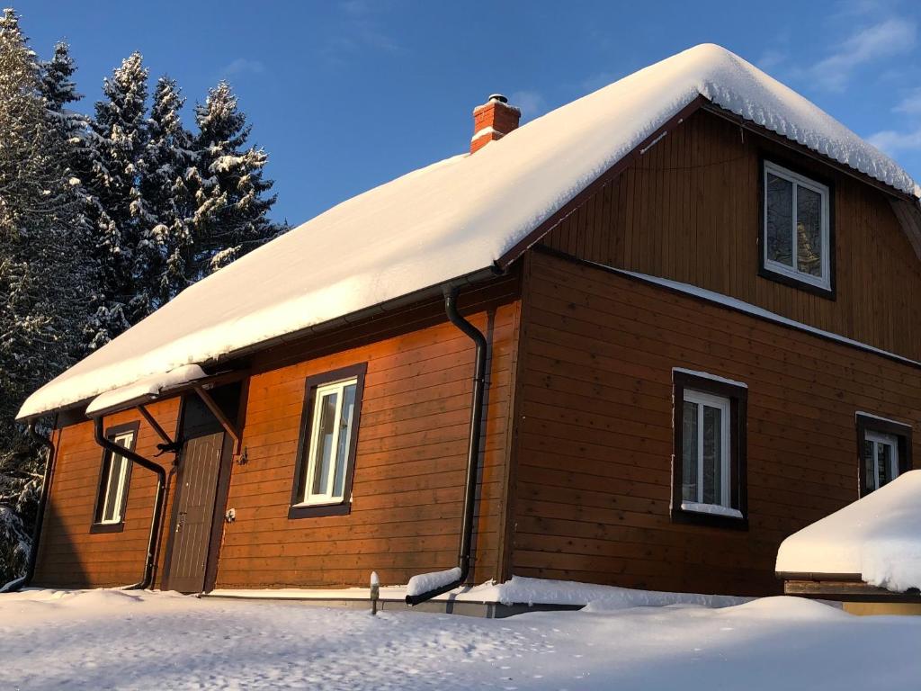a small wooden house with snow on the roof at Ezera Pērle in Ķeipene
