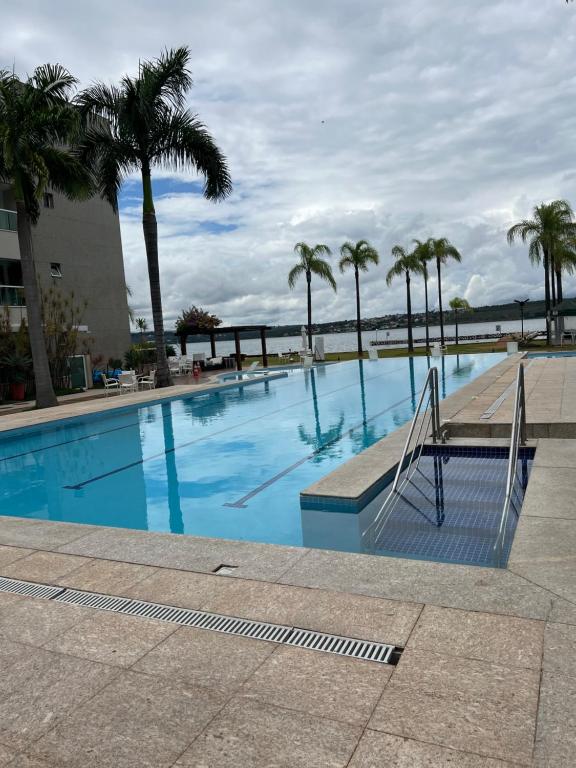 a swimming pool with palm trees and a bench at Brisas do Lago em Brasília in Brasilia