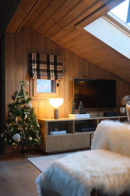 un salon avec un arbre de Noël et une télévision dans l'établissement Appartement avec vue sur les Dômes du Miage, aux Contamines-Montjoie