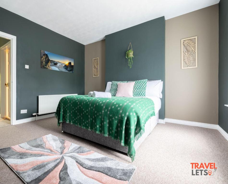 ein Schlafzimmer mit einem Bett mit einer grünen Decke in der Unterkunft Coastal Cottages in Ballycastle