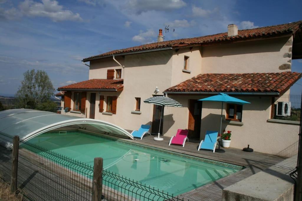 une maison dotée d'une piscine avec des chaises et un parasol dans l'établissement Gîte La ferme de Taverne-Piscine privée chauffée, à Saint-Martin-la-Sauveté