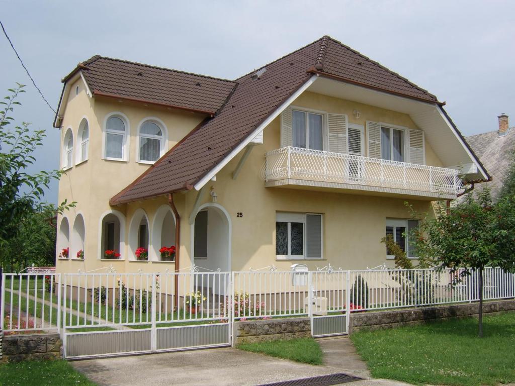 uma casa amarela com uma cerca branca em Susanne Apartman em Balatonboglár