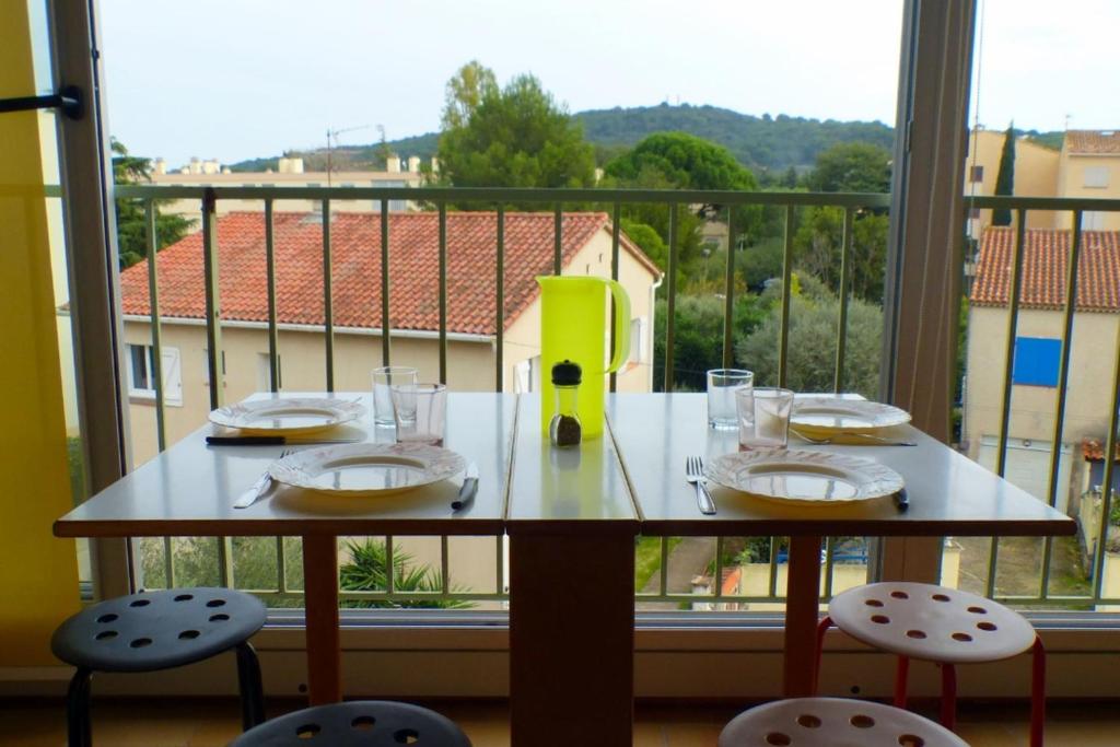 een tafel met stoelen voor een groot raam bij Charming studio with balcony in Sanary-sur-Mer in Sanary-sur-Mer
