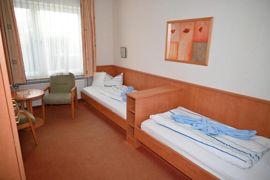 a room with two beds and a chair at Zweibettzimmer-03-EG in Borkum