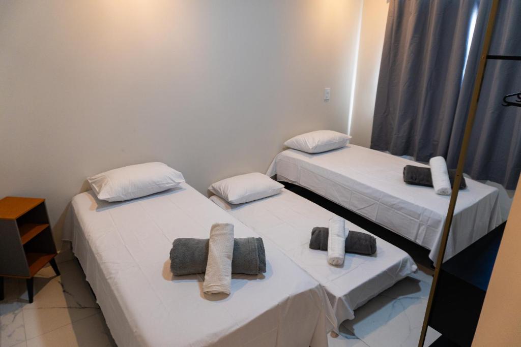 two beds in a room with towels on them at Condomínio Triângulo da Embaúba in Porto Seguro