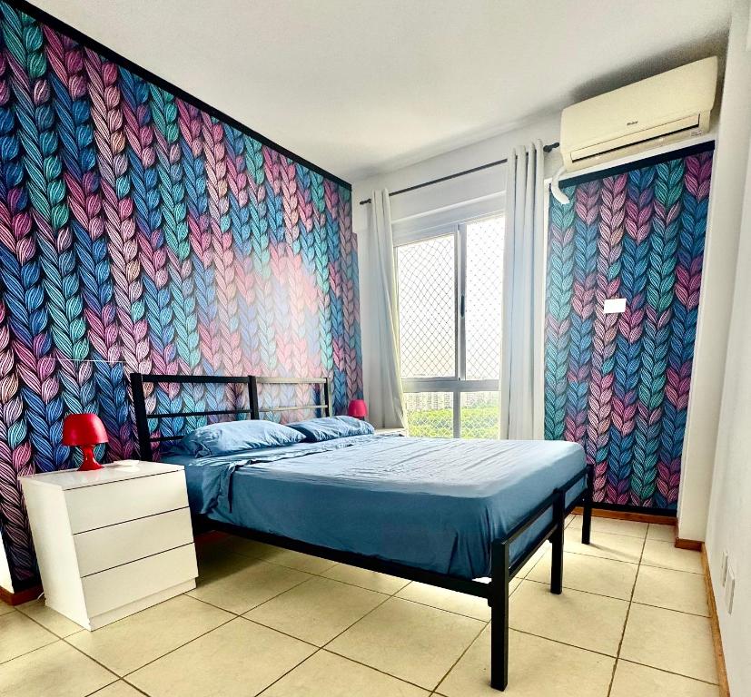 a bedroom with a bed with a colorful wallpaper at Apartamento Parque Olímpico in Rio de Janeiro