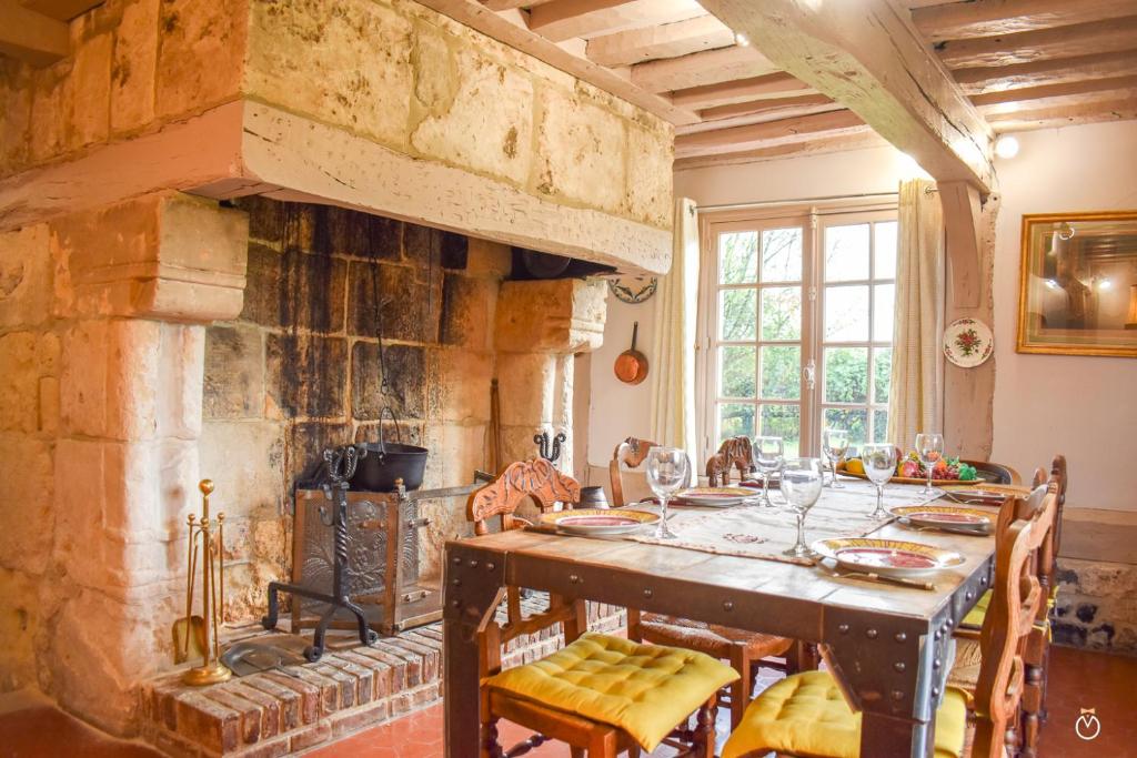 une salle à manger avec une table et une cheminée en pierre dans l'établissement La Closeraie - 10 min d'Honfleur-Deauville 7P, à Saint-Gatien-des-Bois