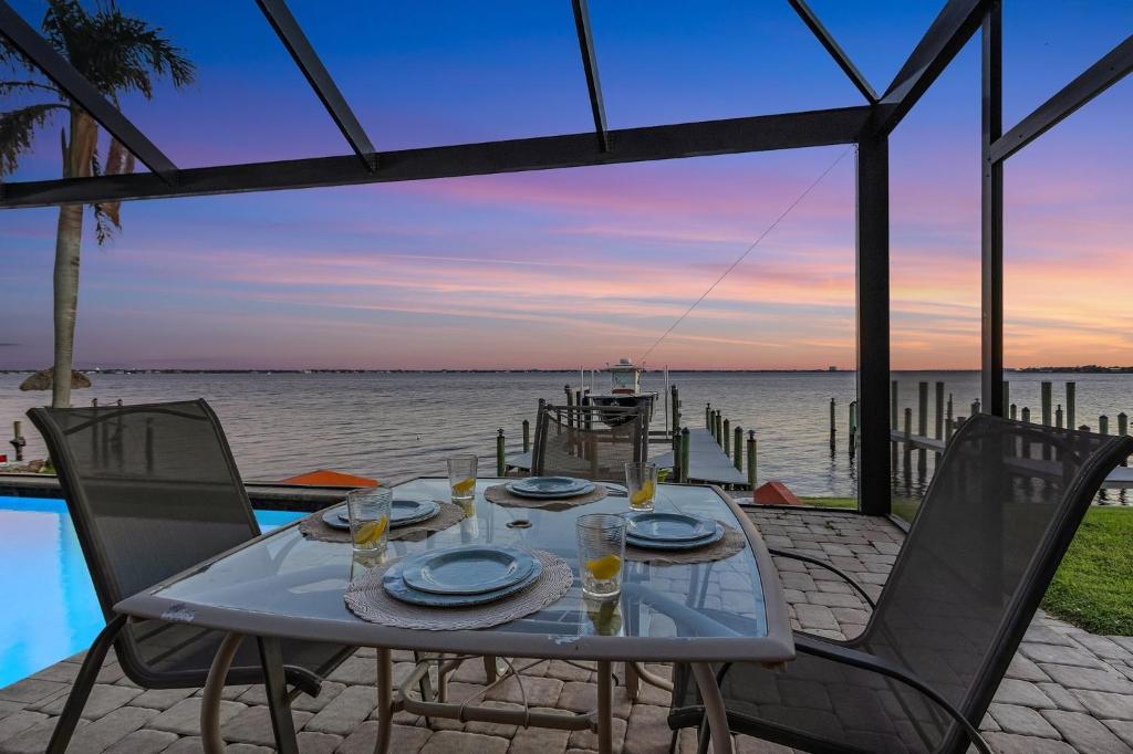 una mesa con vasos y platos junto al agua en Luxury and Elegance! Stunning Riverfront view, Heated Pool - Bayview - Roelens, en Cabo Coral
