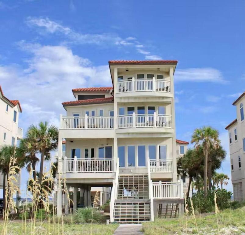 a large white building with palm trees in front of it at Moonlight Sonata-Beachfront-Community Pool in St. George Island