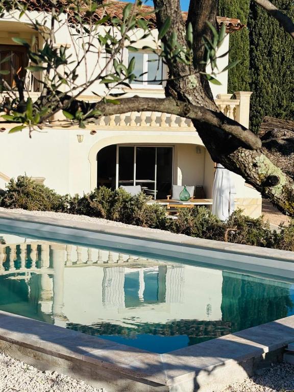 une piscine en face d'une maison avec un arbre dans l'établissement Bas de Villa le Dolce, à La Farlède