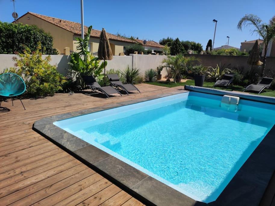 - une piscine sur une terrasse en bois avec des chaises dans l'établissement Villa Carline, à Balaruc-les-Bains