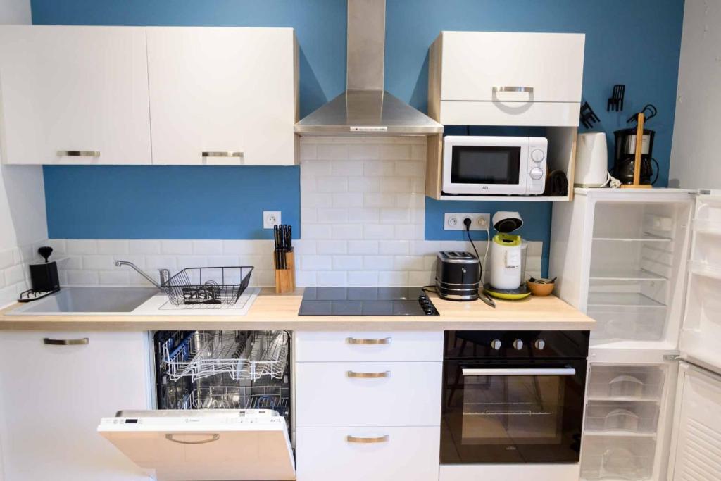 une petite cuisine avec des armoires blanches et un micro-ondes dans l'établissement Les volets blancs, à Lamalou-les-Bains