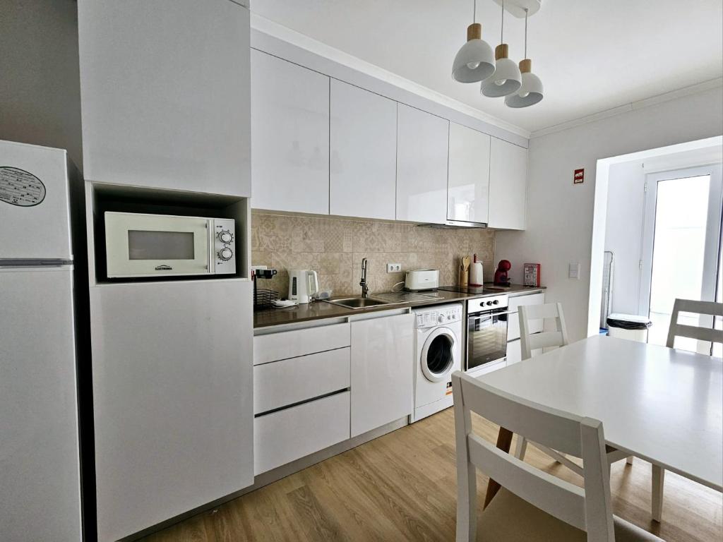 een witte keuken met een tafel en een witte koelkast bij Esperança House 1 in Maia