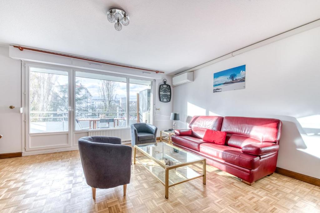 een woonkamer met een rode bank en een glazen tafel bij GuestReady - Tranquil Escape in the City in La Mulatière