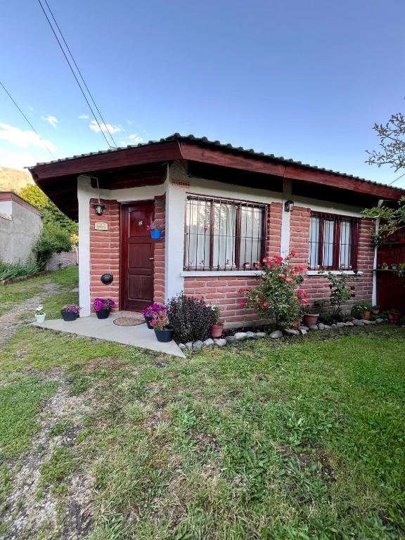 a small house with a red door in a yard at La Casita de Lorena in El Bolsón