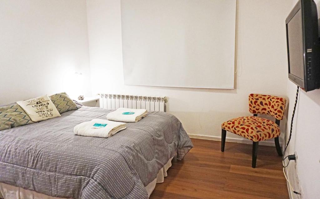 a bedroom with a bed and a tv and a chair at Alojamiento en Ushuaia - Mirador del Beagle in Ushuaia