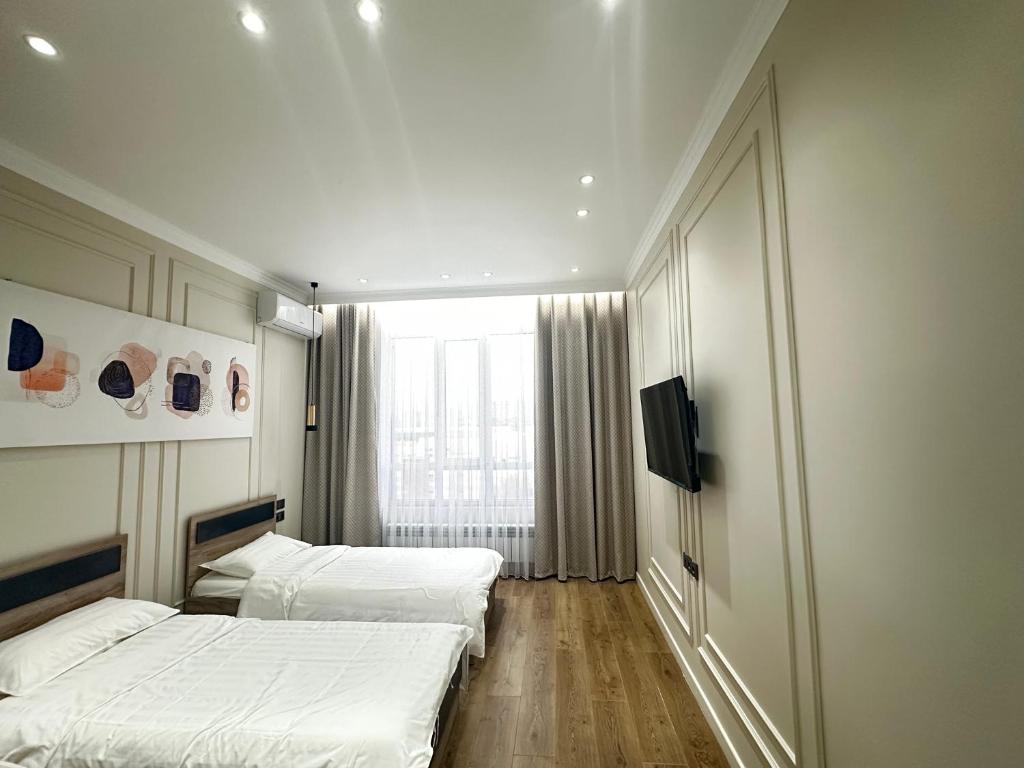 a room with two beds and a television in it at MegaPark Appartments in Almaty