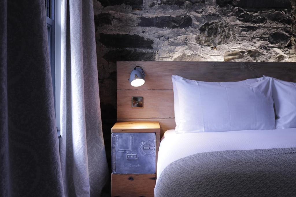 een slaapkamer met een bed met een bakstenen muur bij Suie Hunting Lodge in Killin