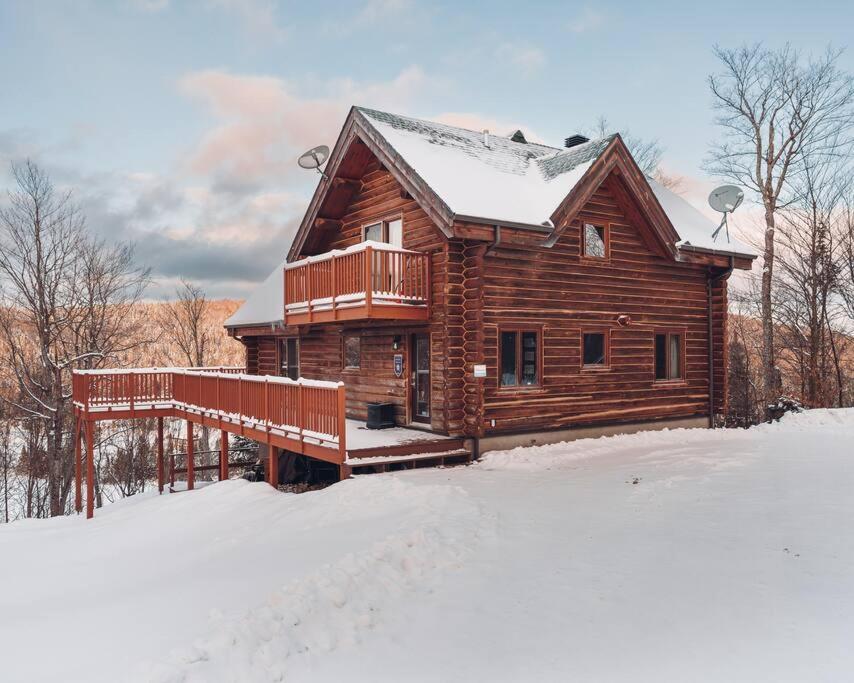a log cabin with a deck in the snow at Le Tranquille in Mont-Blanc