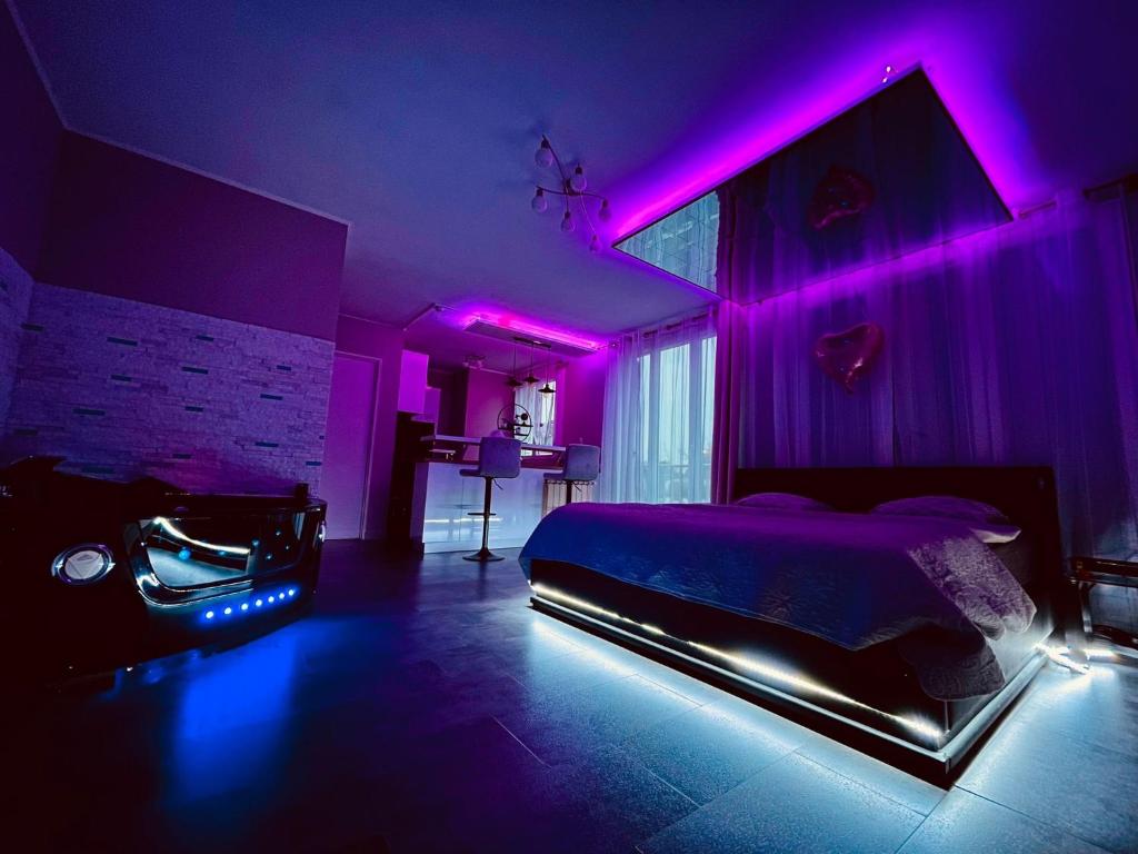 a bedroom with a bed with purple lights on it at Love Room O'Dream, Jacuzzi et Lit King Size in Fleury-les-Aubrais
