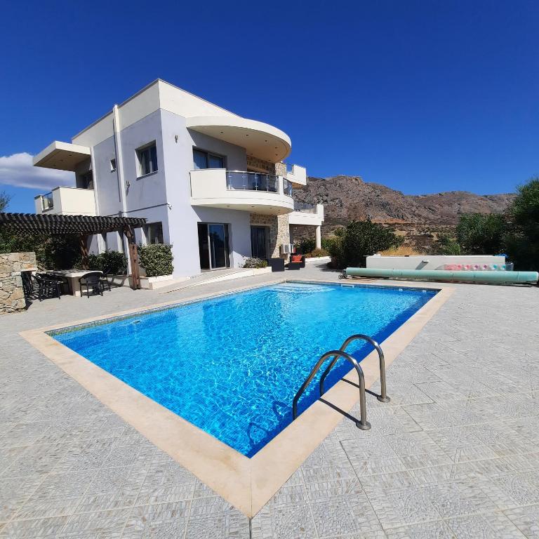 a villa with a swimming pool in front of a house at Villa Danae in Makry Gialos