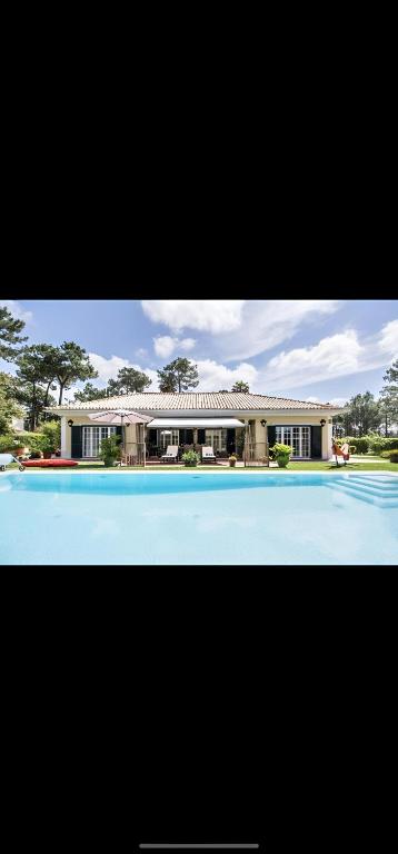 a large house with a swimming pool in front of it at Charming Villa Jarros Private pool & Golf in Aroeira