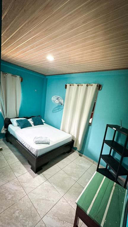 a blue bedroom with a bed and a chair at Hotel Caribbean View in Bastimentos