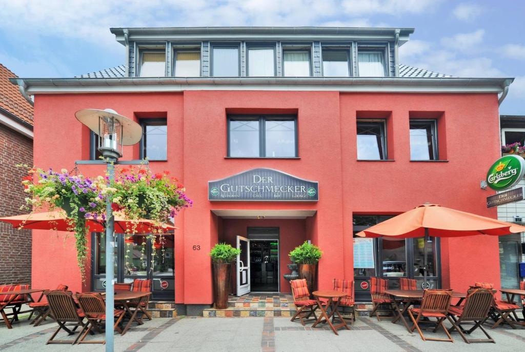 un edificio rojo con mesas y sombrillas delante en Der Gutschmecker Bad Segeberg, en Bad Segeberg