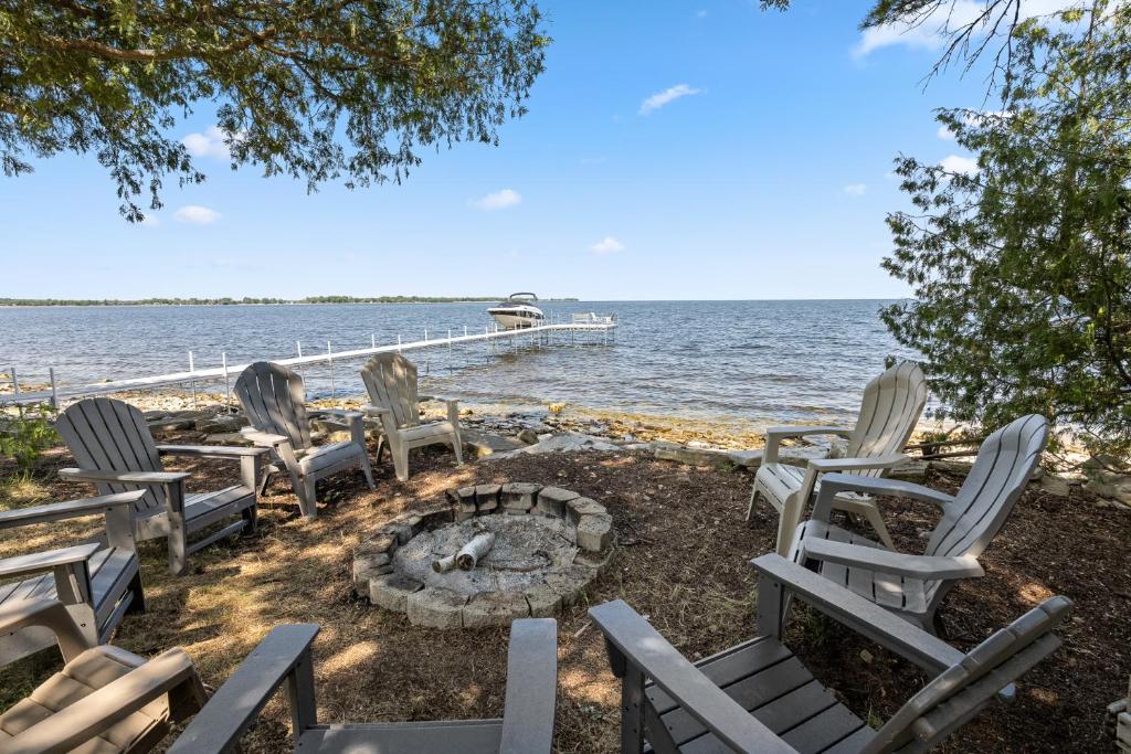 a group of chairs sitting next to the water at Heidaway Cottage by Simple Life Rentals in Sturgeon Bay