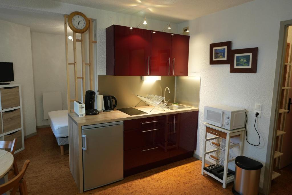 une cuisine avec des armoires rouges et un comptoir dans l'établissement appartement 4 personnes, ascenseur, balcon, 100 m du télécabine, à Cauterets