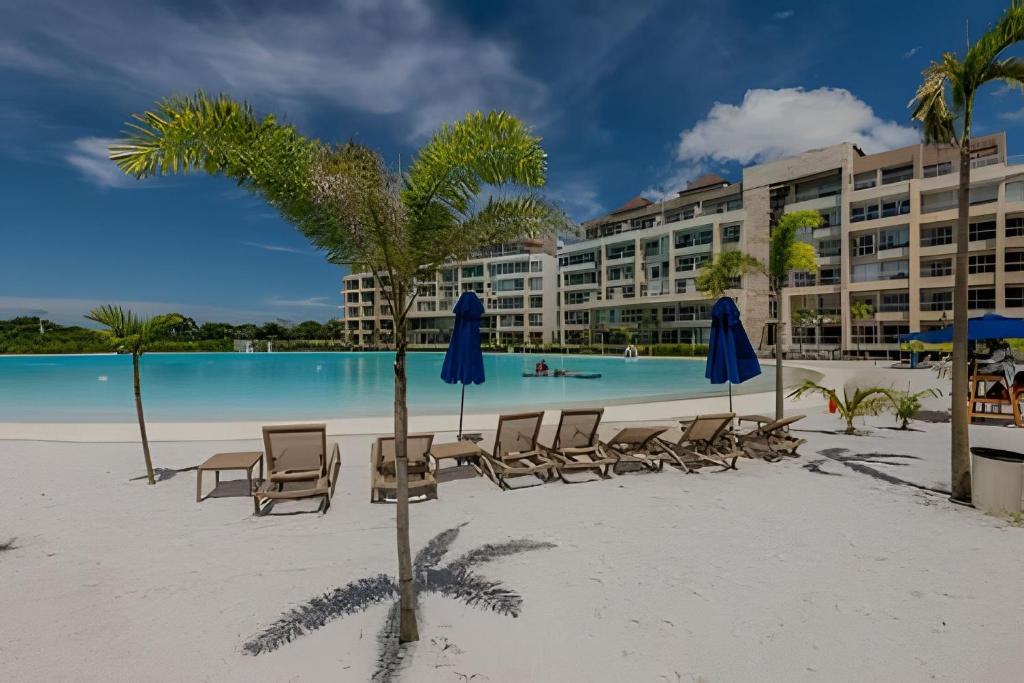 a beach with chairs and umbrellas and a swimming pool at Nuevo, Exclusivo Apto 2BR Laguna Cristalina in Cartagena de Indias