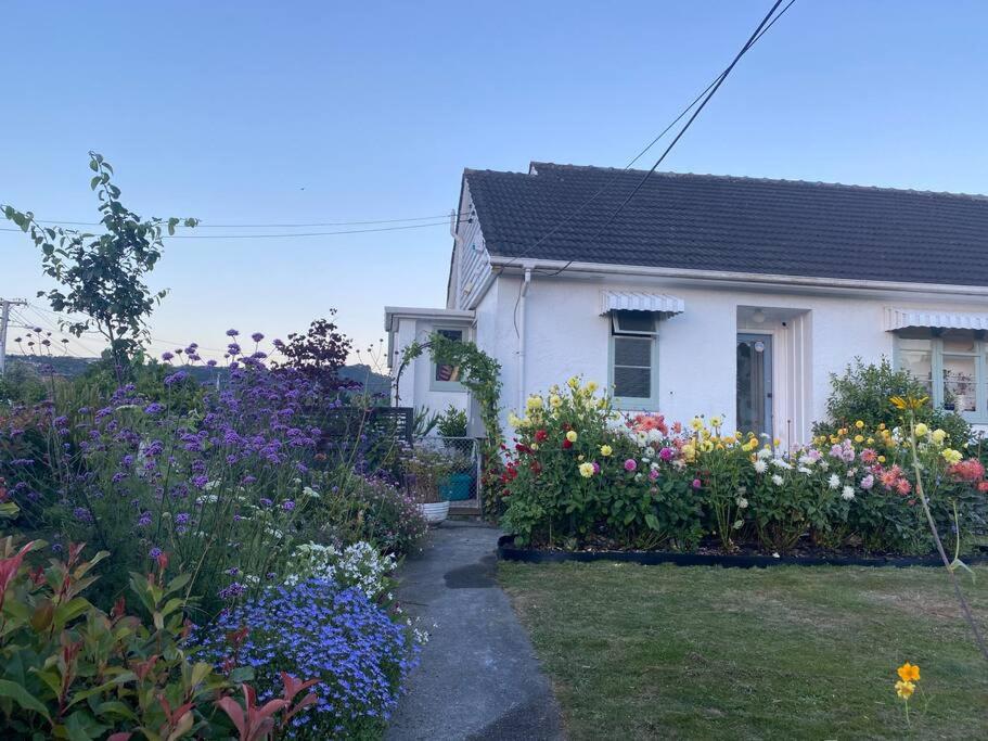 a white house with flowers in front of it at Sunny 3 Bedroom with garden close to hospital in Lower Hutt