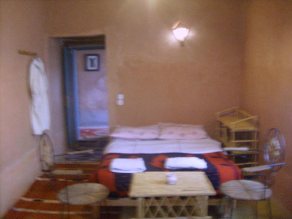 a room with a bed and a table and chairs at auberge restau tombouctou in Aït Benhaddou
