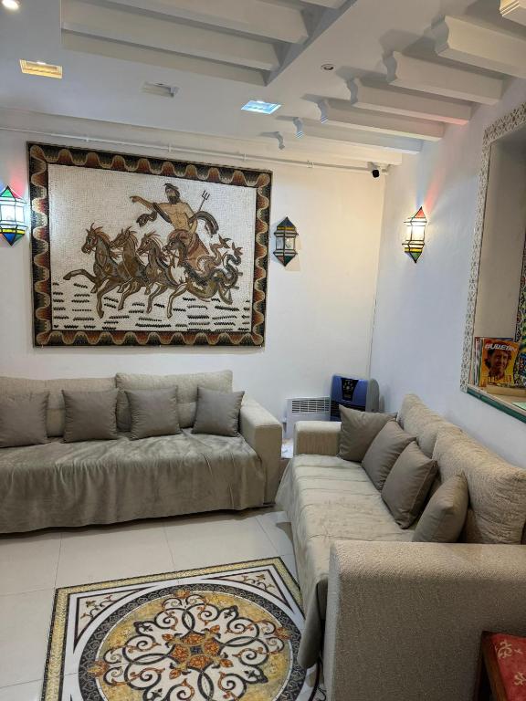 a living room with couches and a painting on the wall at Dar El Mahdia by Daldoul in Mahdia