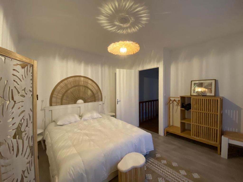 a bedroom with a large white bed and a chandelier at La Maison du Lavoir in Port-en-Bessin-Huppain