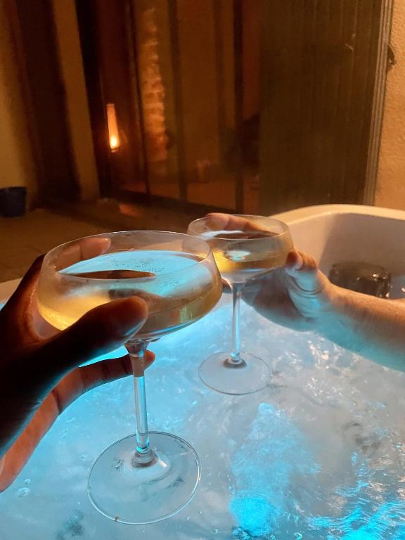 une personne tenant deux verres à vin dans une baignoire dans l'établissement Maison de village avec jacuzzi et garage, à Bédoin