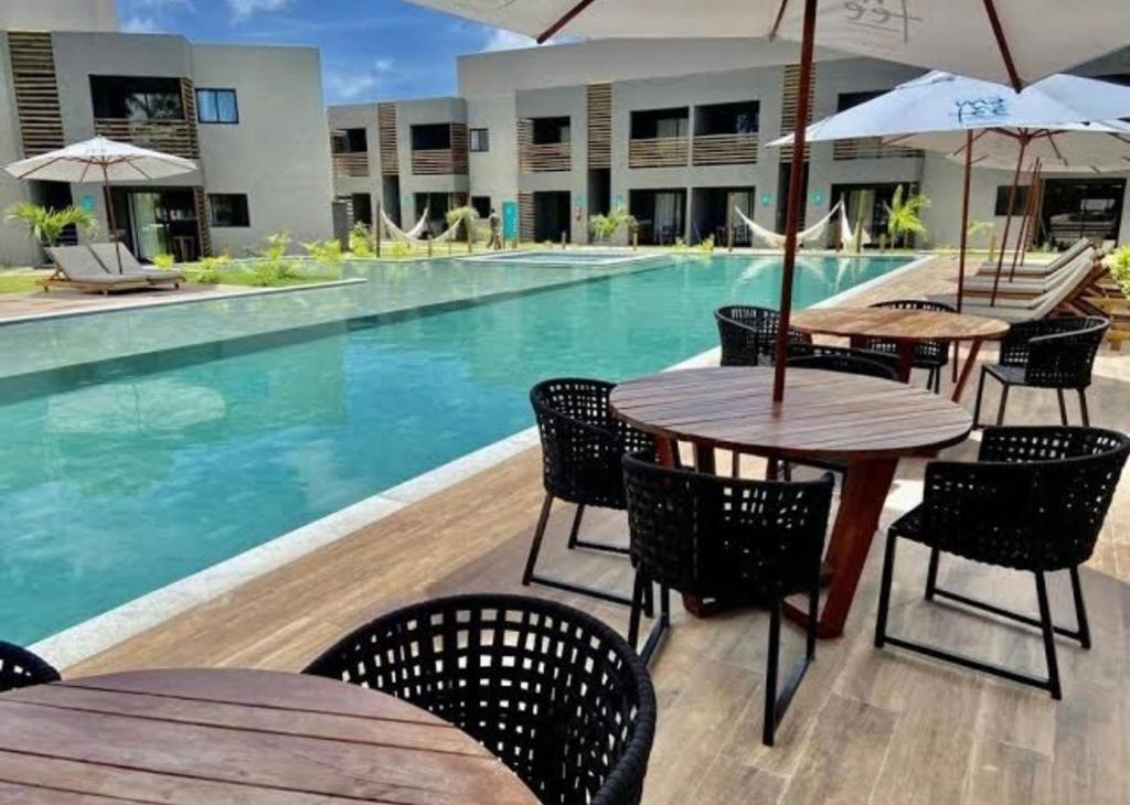 a swimming pool with tables and chairs next to a building at VILLAS M PATACHO - Aluga Apto F001 in Pôrto de Pedras