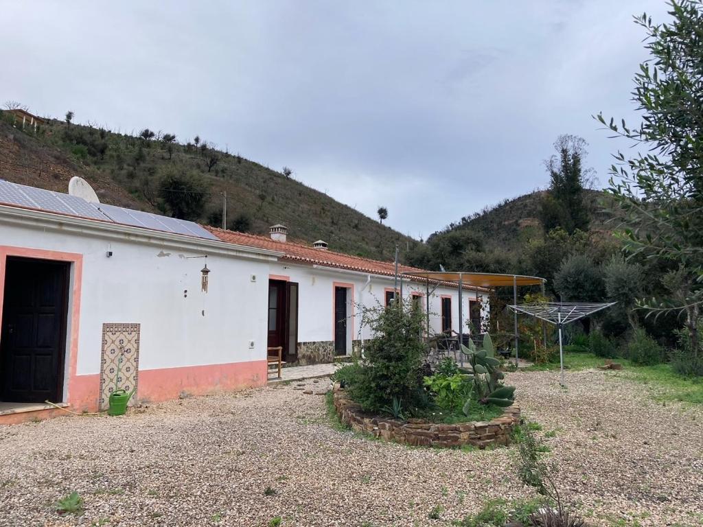 a white house with a mountain in the background at Oleiro de Cima in São Teotónio