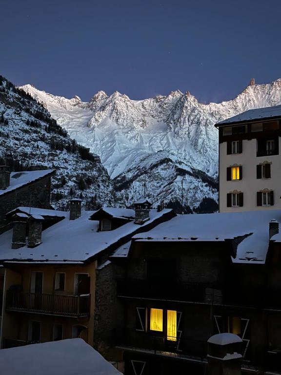 a building with snow covered mountains in the background at Au Coeur de Courmayeur in Courmayeur