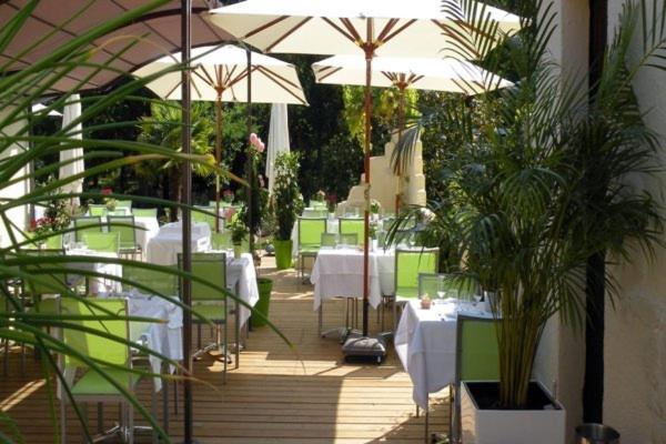 a restaurant with white tables and white umbrellas at Logis Le Pont Bernet in Le Pian-Médoc