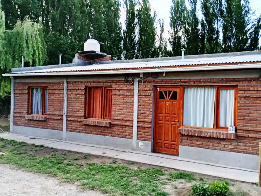 a small brick building with a red door at departamento por día ruta 41 2 in Los Antiguos
