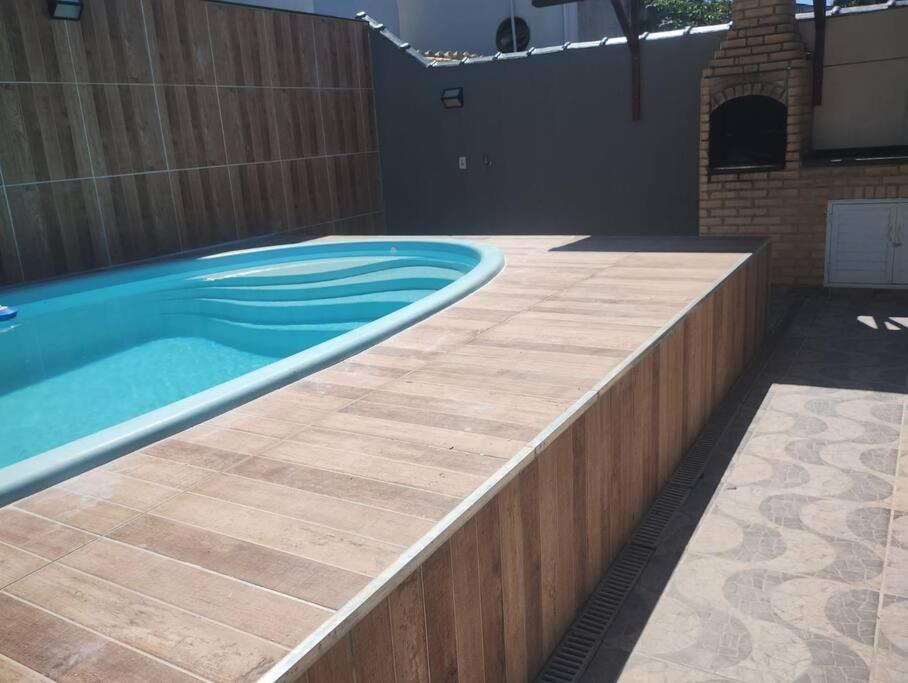 Una piscina en un patio trasero con un muro de contención de madera. en Casa de praia meu bom, en Rio das Ostras