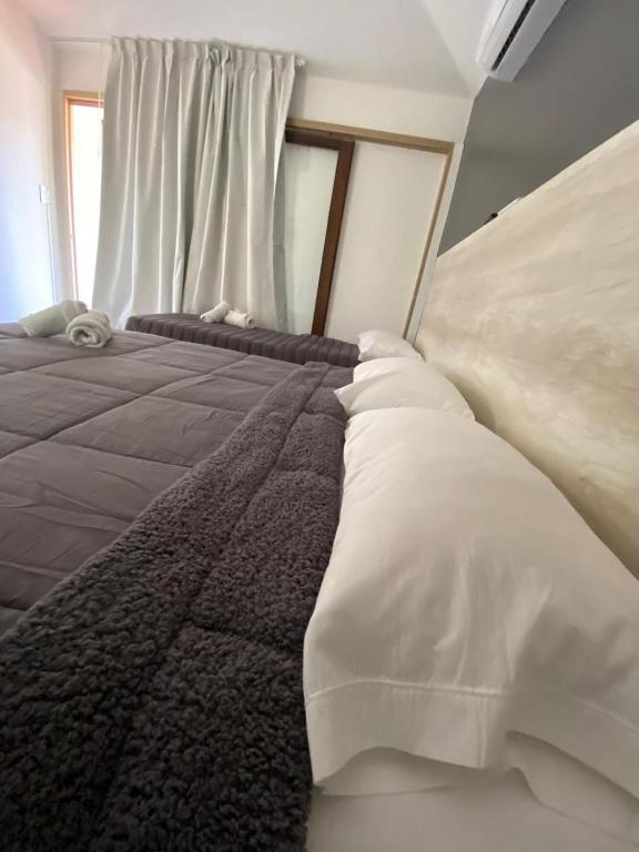 a bedroom with a bed with white sheets and a window at Complejo Turístico Chaya in La Rioja
