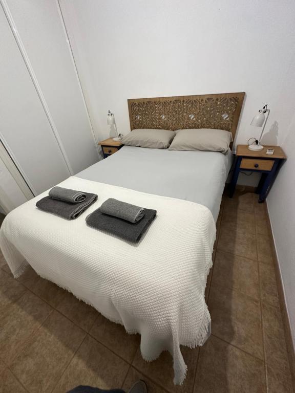 a bedroom with a white bed with two towels on it at El Playaiso de San José in San José