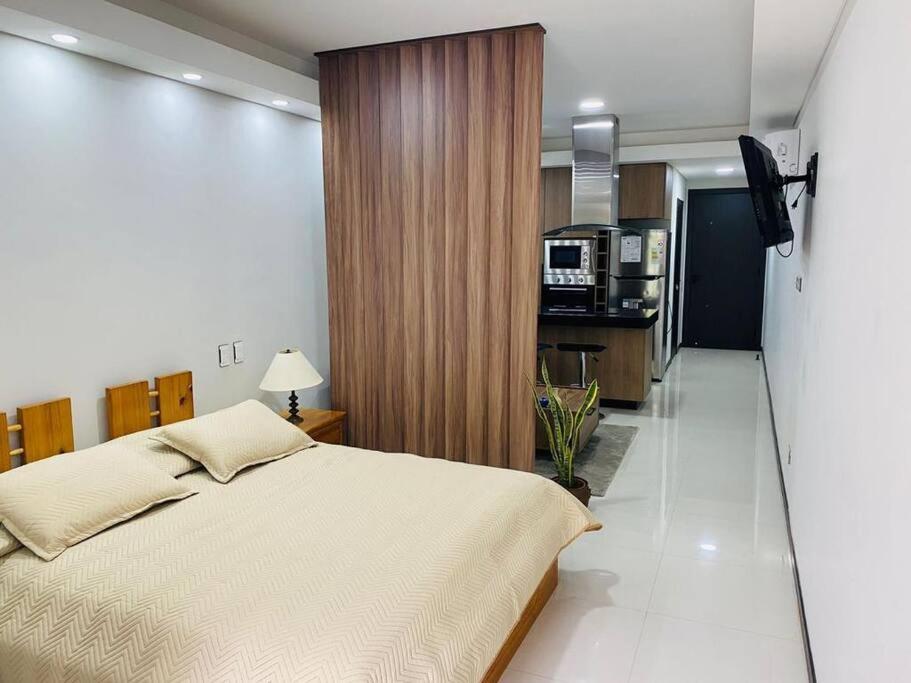 una camera da letto con un letto grande e una cucina di Mono ambiente en Equipetrol - Edificio La Foret a Santa Cruz de la Sierra