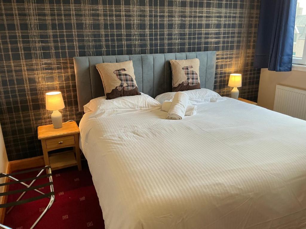un grande letto bianco con due cuscini sopra di Seaview John O Groats Hotel a John O Groats