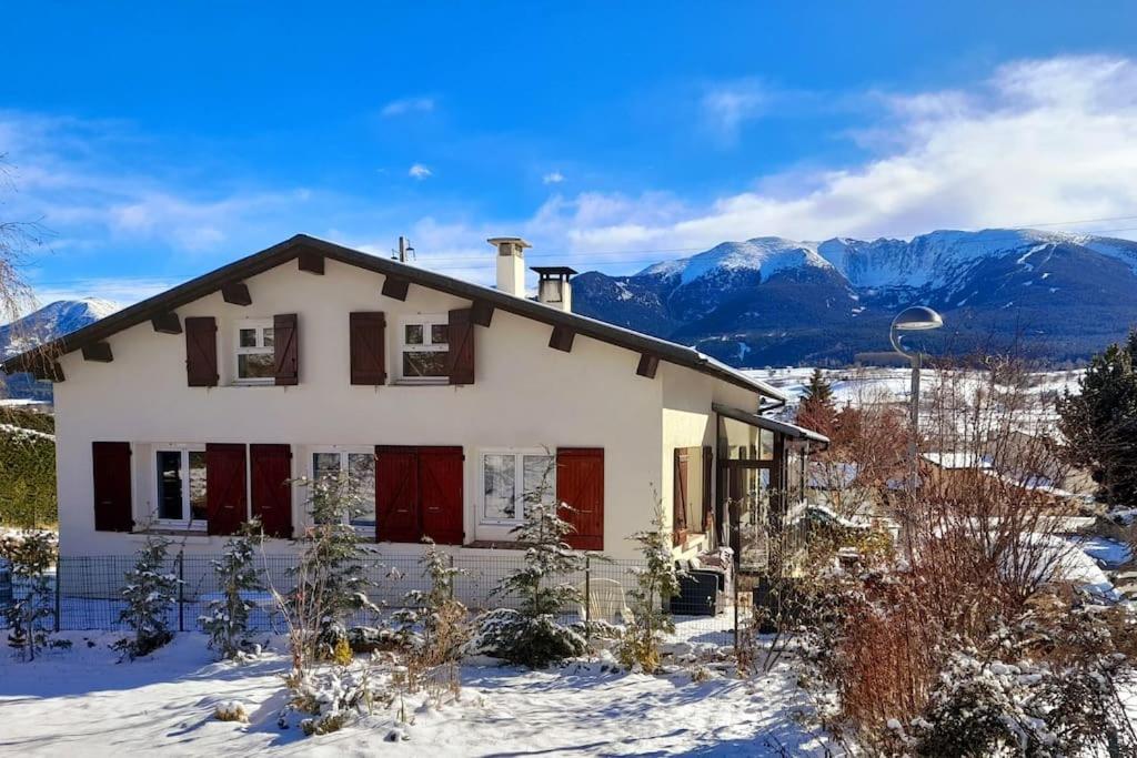 une maison dans la neige avec des montagnes en arrière-plan dans l'établissement Maison à 5 min des pistes, à La Cabanasse